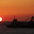 写真: 小さいだるま夕日とクレーン船