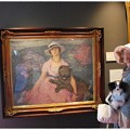 写真: 犬を抱く女性の絵画の前で