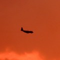 写真: 夕焼けの中を飛ぶ空自輸送機