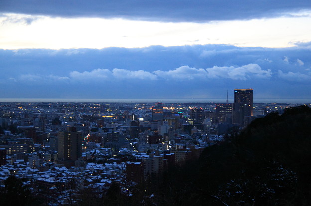 写真: 金沢市　雪の街並みと日本海　　日が沈んで